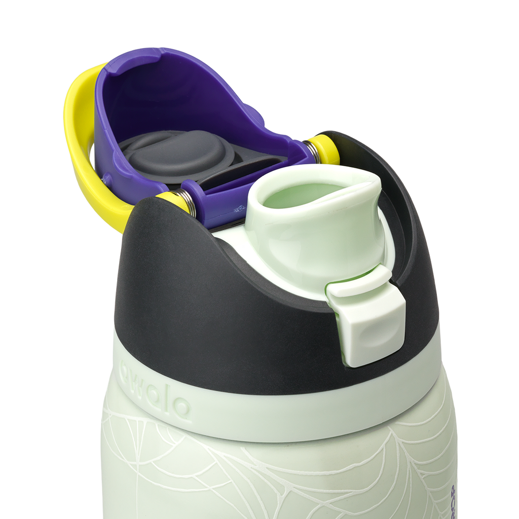 Owala FreeSip 32oz in RIP, flip cap open showing yellow-green FreeSip spout, purple lid interior with gray silicone seal, dark charcoal lid, on pale mint green body with white skeleton-hand pattern; glows in the dark